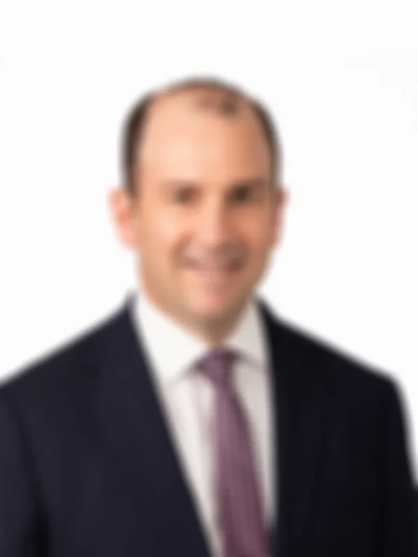 Peter Christopherson in a dark suit and patterned tie smiling against a plain white background.