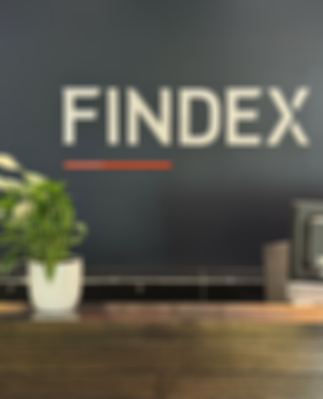 Findex Hastings office reception desk with a potted plant and computer monitor in front of a wall displaying the word "FINDEX".