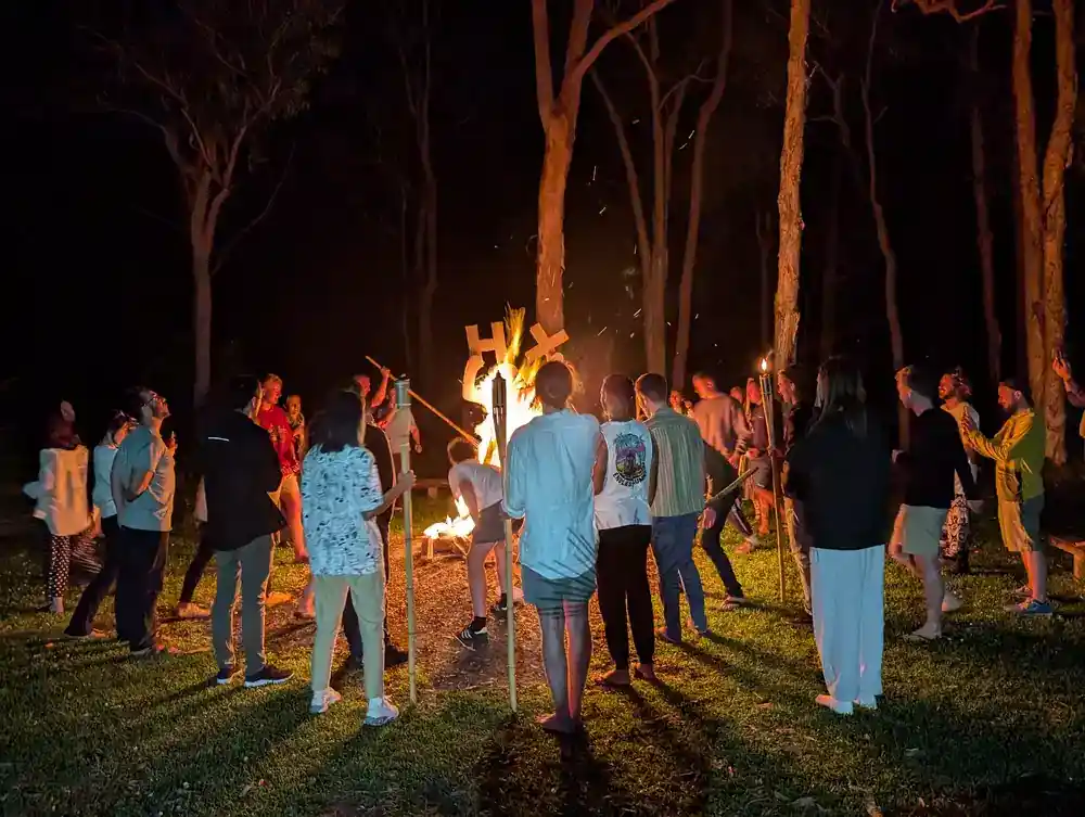 The Humanitix team standing around a bonfire of a statue holding a HX