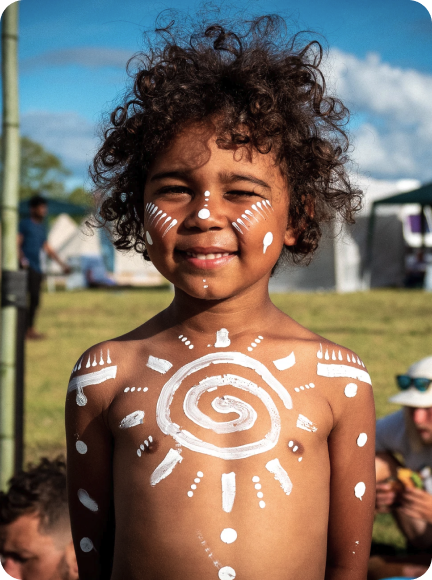 Boy with curly hair and white patterns painted on his face and chest