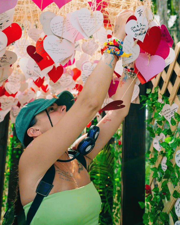 A festival goer trying a heart onto the Okeechobee x Humanitix portal of love installation
