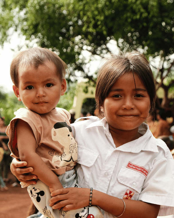 A young girl holding a toddler in her arms