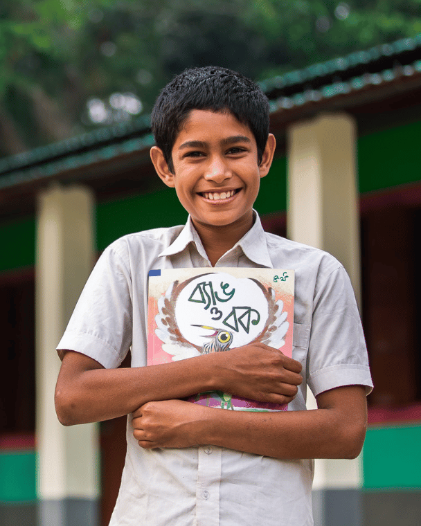 A smiling boy hugging a book