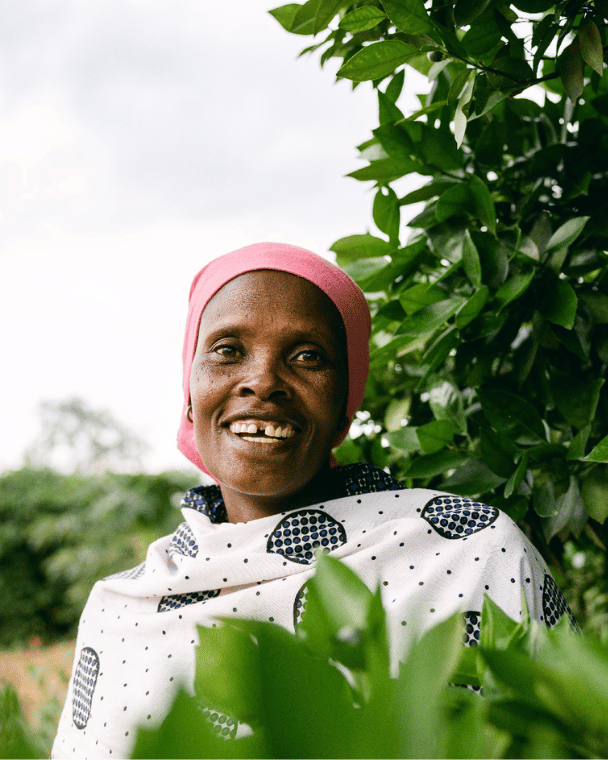 A smiling woman wearing a bandana among the trees