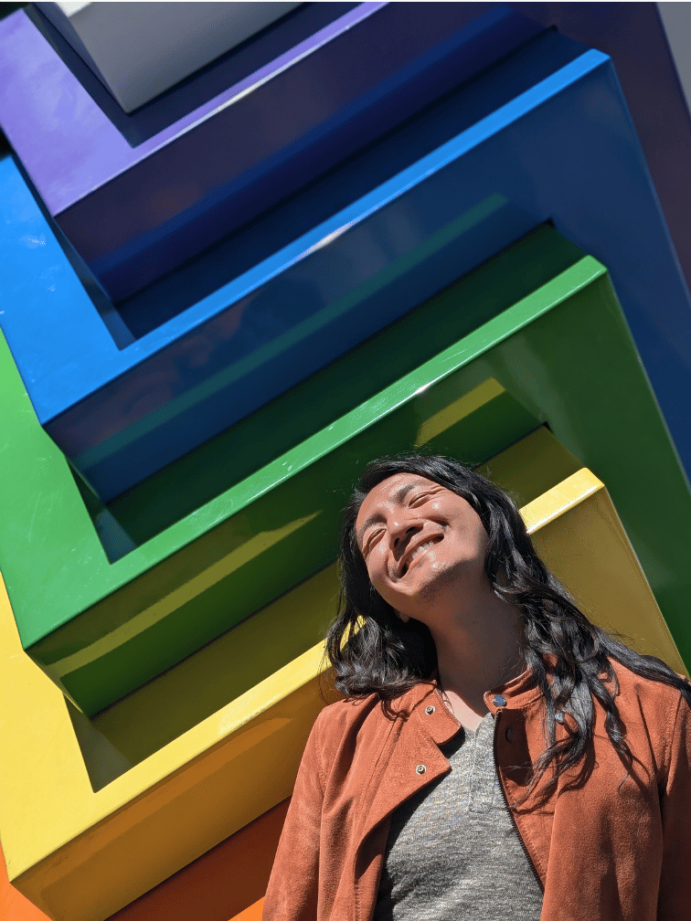 Jeremy standing in front of a rainbow sculpture on GiveOut Day
