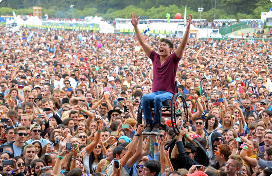 A festival goer being lifted up by a crowd in a wheelchair