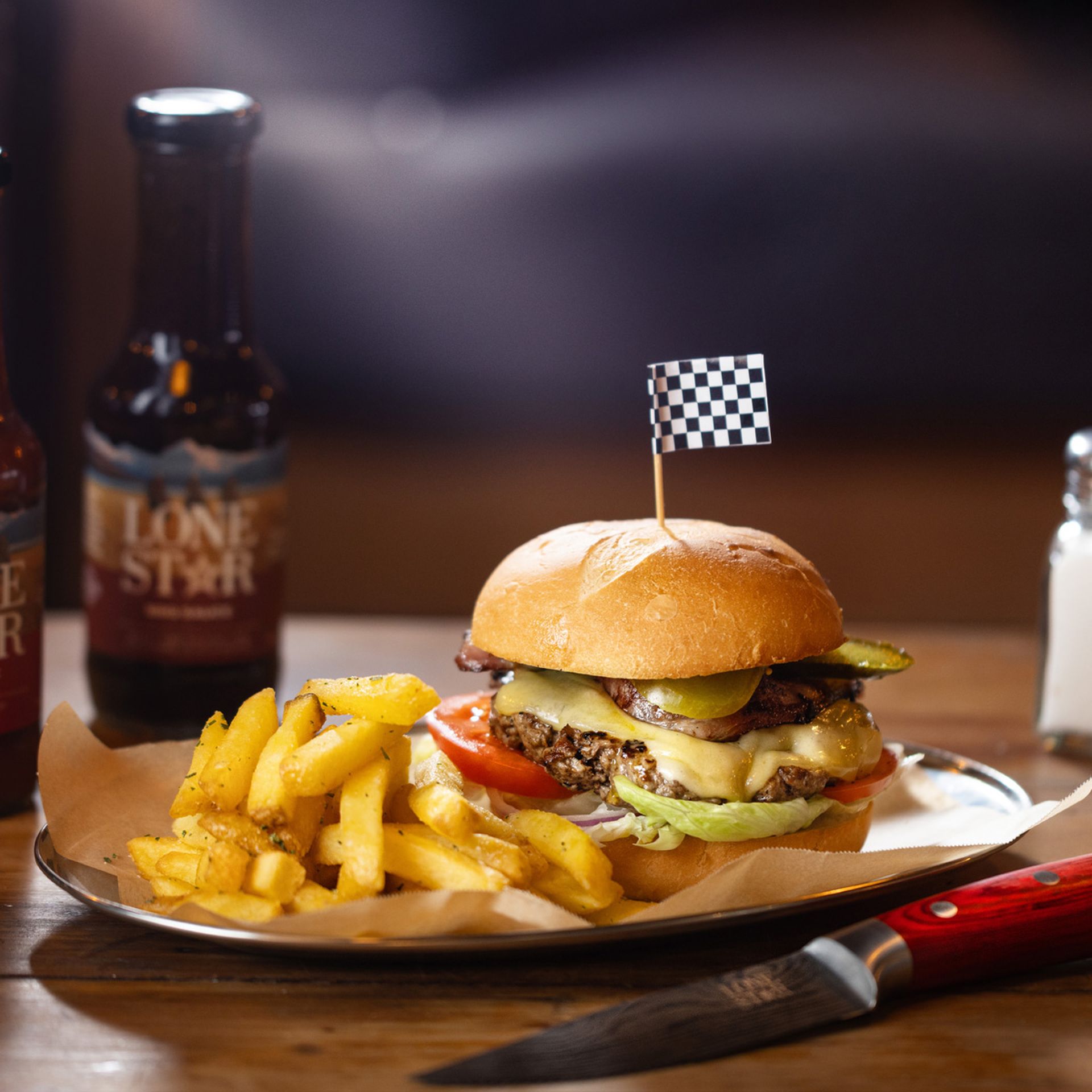 Gerhard Burger from Lone Star NZ with fries – stacked beef burger in a sourdough bun with Swiss cheese, bacon, and fresh vegetables. Perfect for anyone searching food near me.