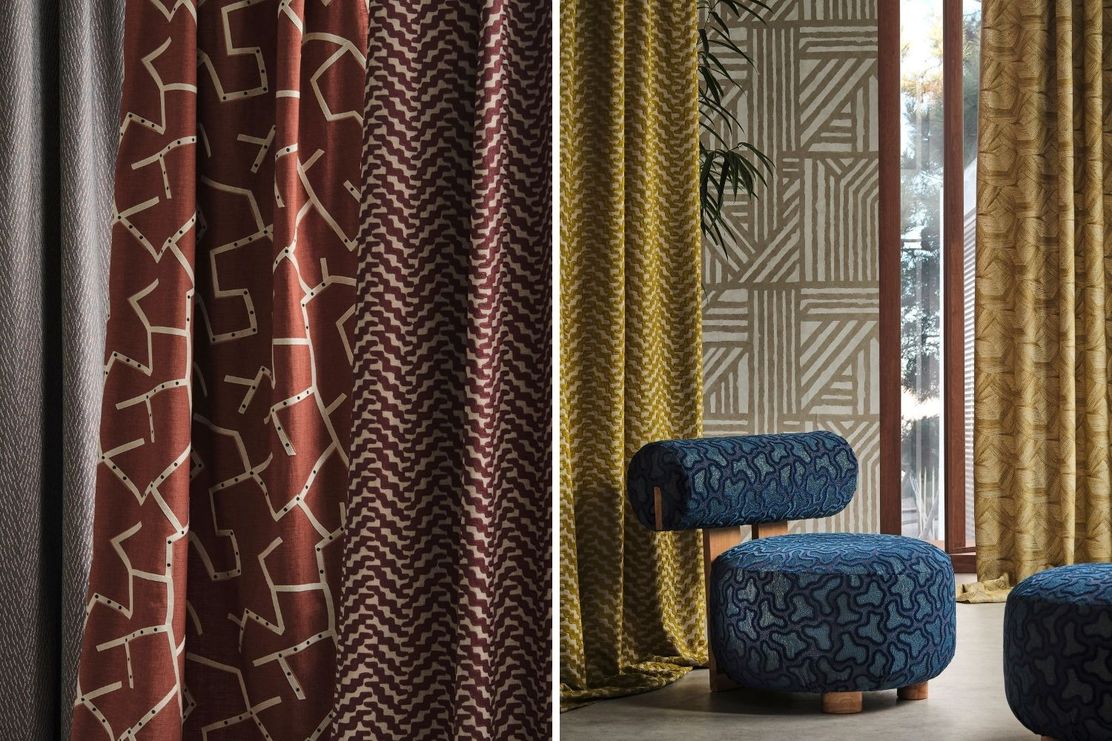 Patterned curtains in red, yellow, and grey hang beside a window. A blue patterned stool and a glimpse of indoor plants are visible.