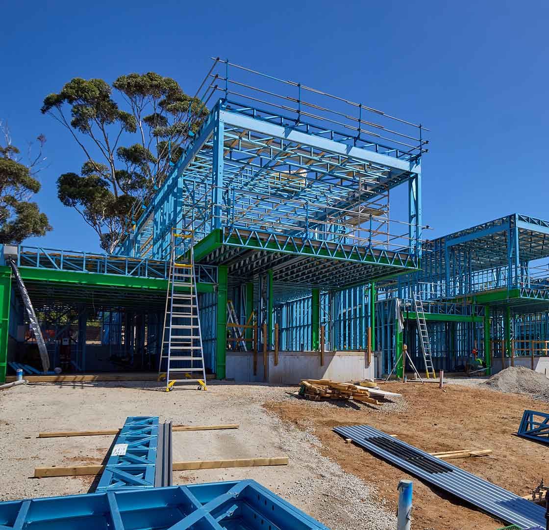 TRUECORE Steel-framed house under construction on The Block, against a clear blue sky.