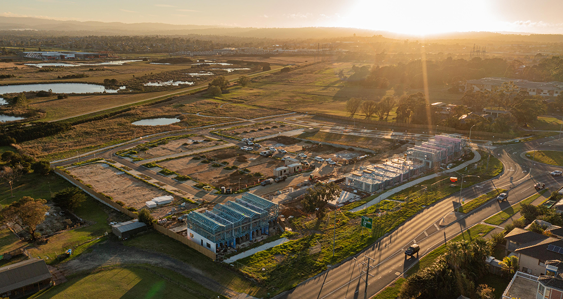 Aerial view of Creation Homes housing development at Hampton Park under construction at sunset, surrounded by fields and roads.