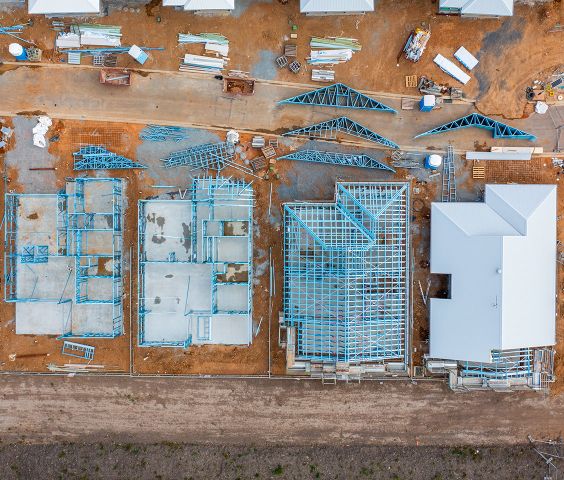 Aerial view of a construction site showing partially built houses with blue steel framing made from TRUECORE steel.