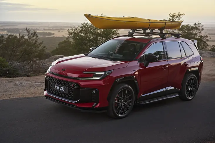 Red Toyota RAV4 with a yellow kayak on the roof, parked at sunset