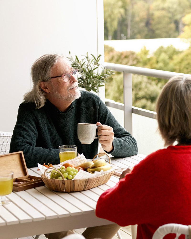 An older couple having breakfast together on their apartment balcony