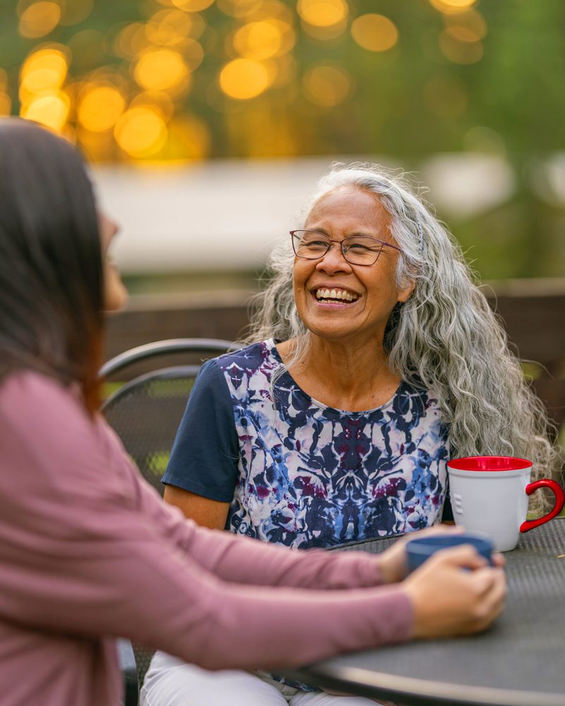 Two women talking over coffee at an outdoor table
