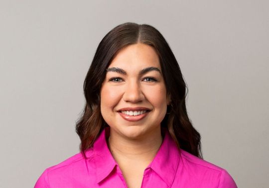 Portrait of Paige Cullin wearing a bright pink McGrath Foundation uniform shirt.