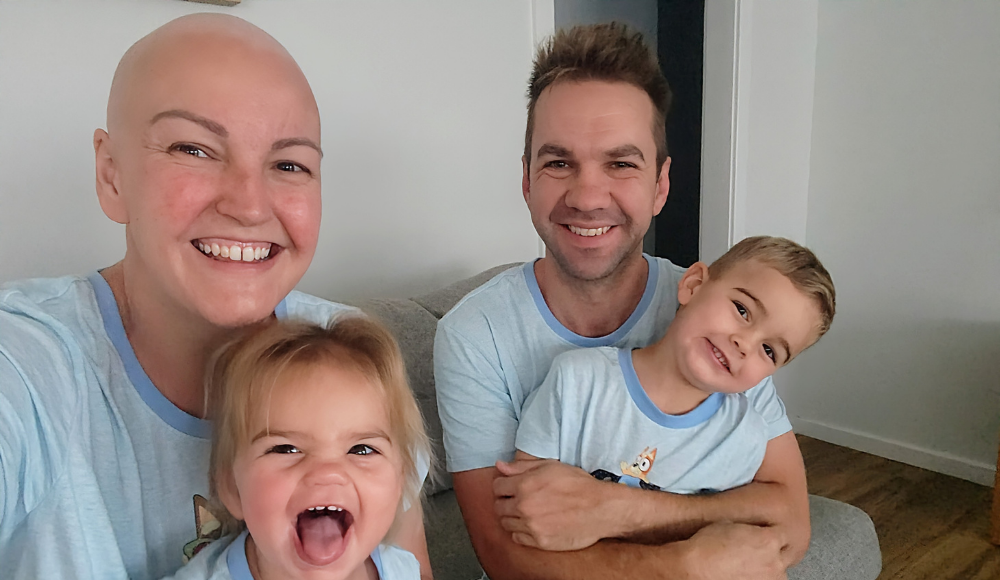 A selfie taken by Kirby when she had lost her hair, sitting down with her husband and two children, all in matching Bluey pyjamas.