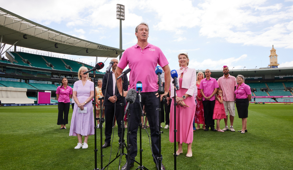 Glenn McGrath standing with a group of people on the Sydney Cricket Ground field talking to media
