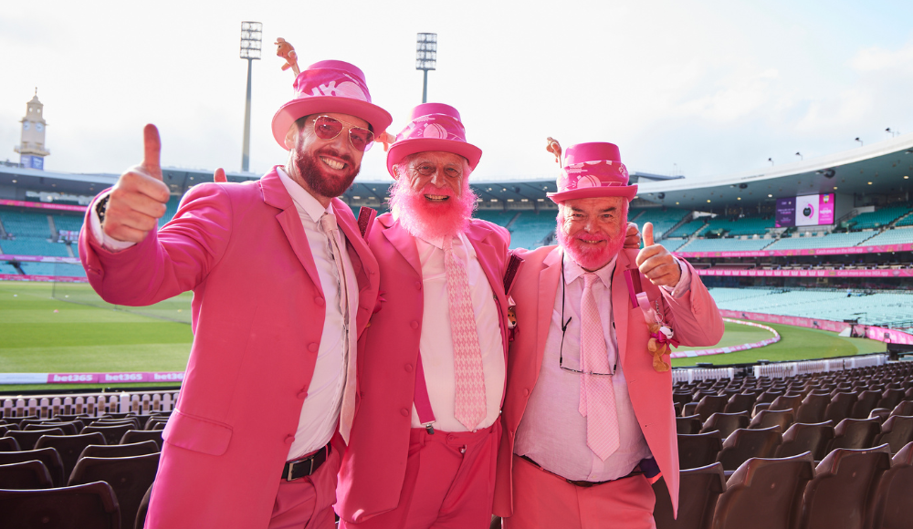 Three men dressed in pink standing in front of the field at the SCG.