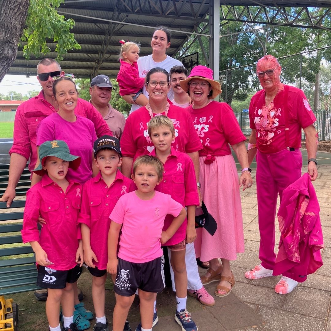 Group of adults and children dressed in pink at an outdoor community fundraising event.