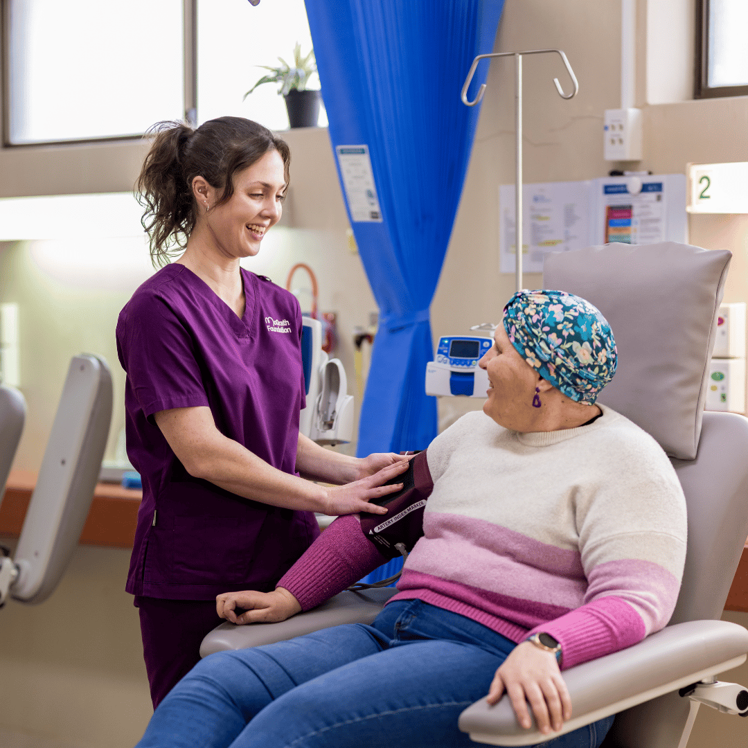 McGrath Cancer Care Nurse checks a patient's blood pressure while the patient receives treatment in a clinical setting.