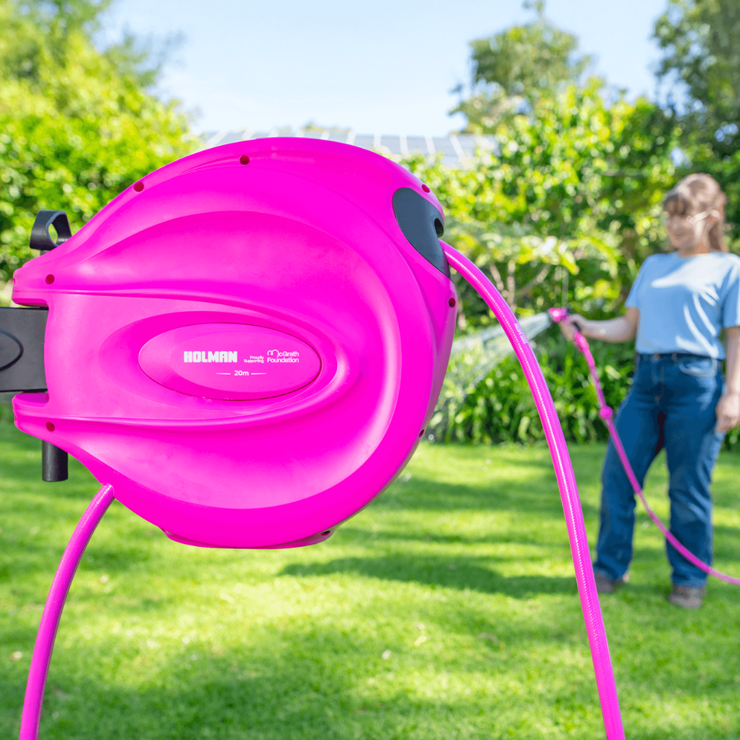 Holman Retractable Hose Reel and a person standing behind watering the lawn.