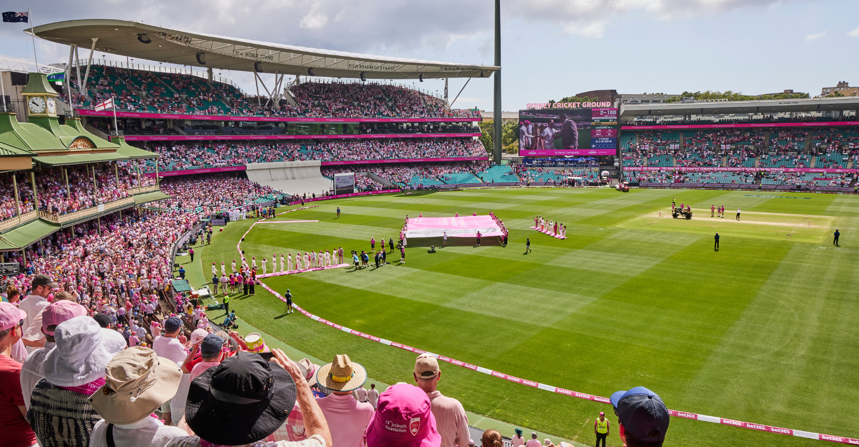 Aerial photo from the stand of the SCG looking down at the pitch as the Australian mens cricket team walk out to present Glenn McGrath with their baggy pinks