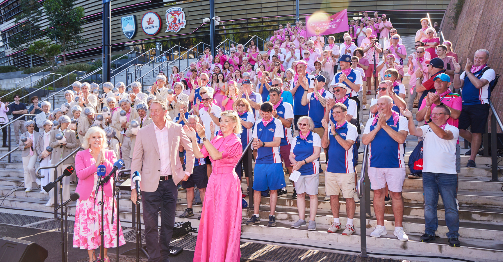 Group of people standing on the steps at the entrance to Alianz Stadium with Glenn McGrath, Tracy Bevan and Holly Masters