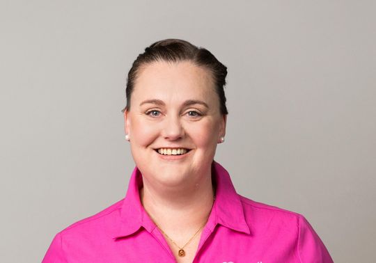 Eva Driver wearing a pink McGrath Foundation shirt against a light grey background