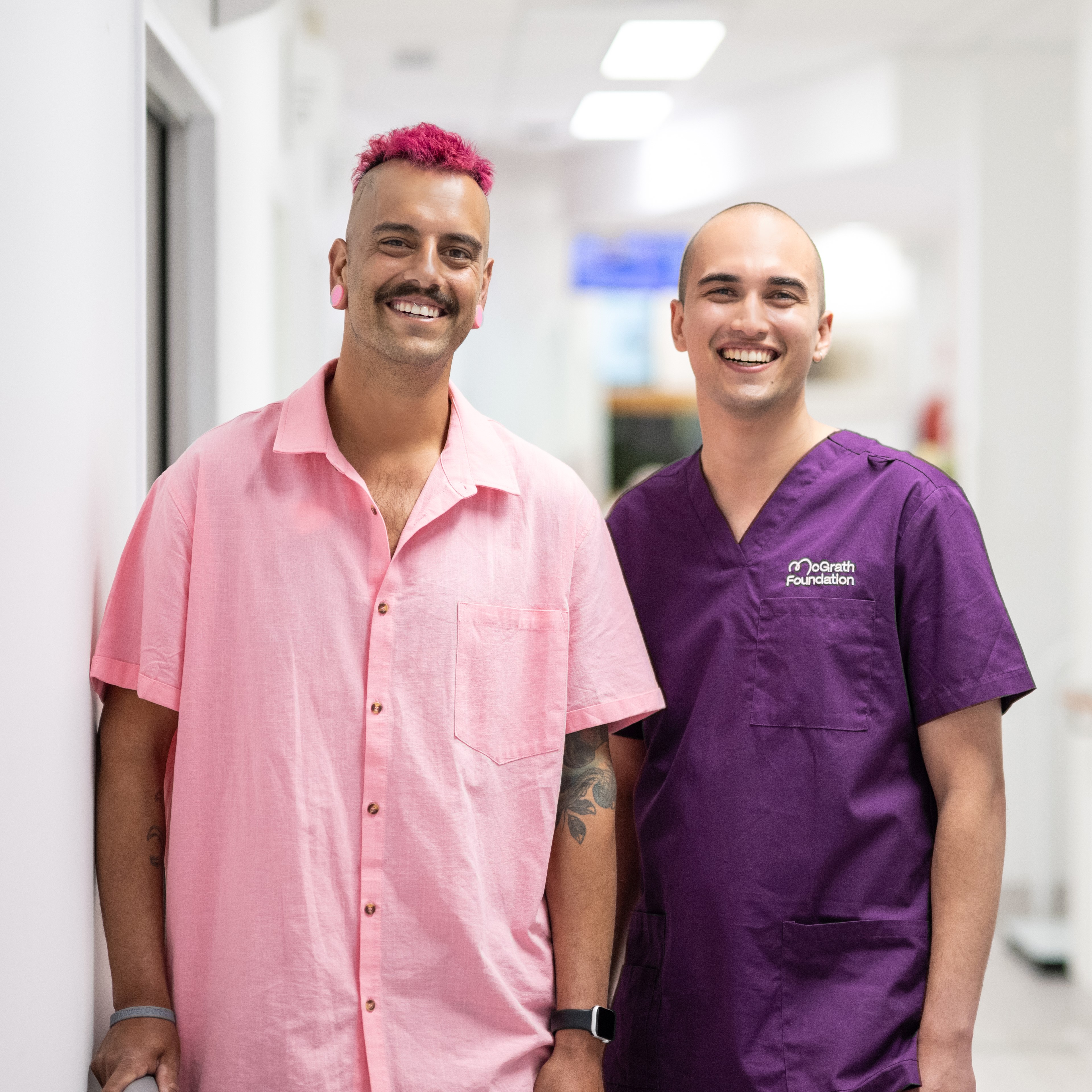 Matt and his McGrath Cancer Care Nurse, Jordan standing in the hallway of a health care facility looking at the camera and smiling