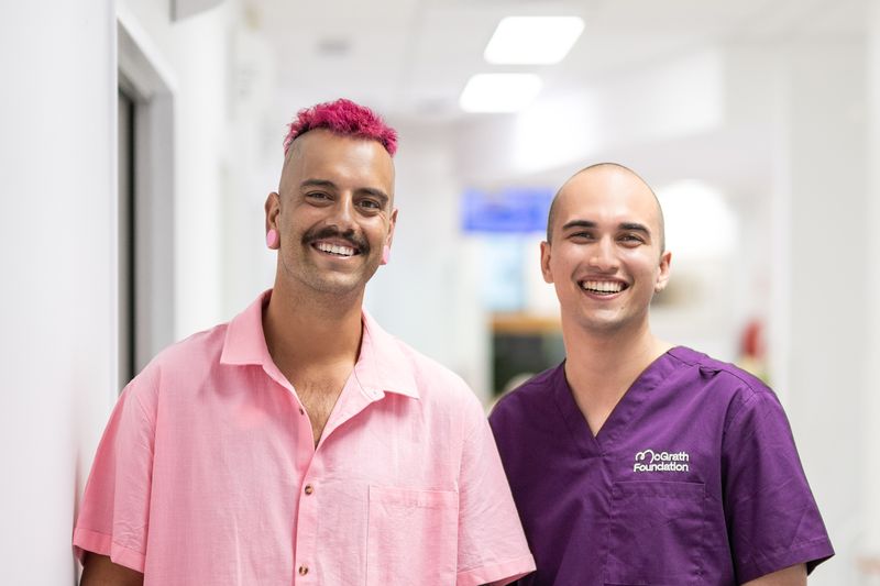 Matt and his McGrath Cancer Care Nurse, Jordan standing in the hallway of a health care facility looking at the camera and smiling