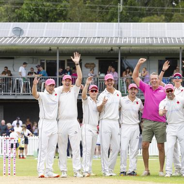 Glenn McGrath standing with cricket players dressed in cricket whites and McGrath Foundation caps