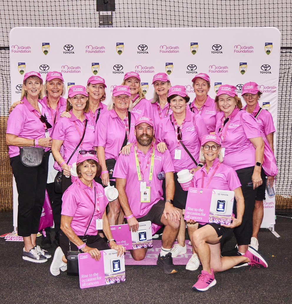 Group of volunteers in pink pose for a photo with fundraising signs at the Pink Test.
