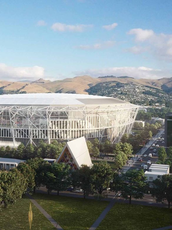 Wide view of a modern stadium with a geometric facade, surrounded by trees and urban buildings, set against a backdrop of rolling hills.