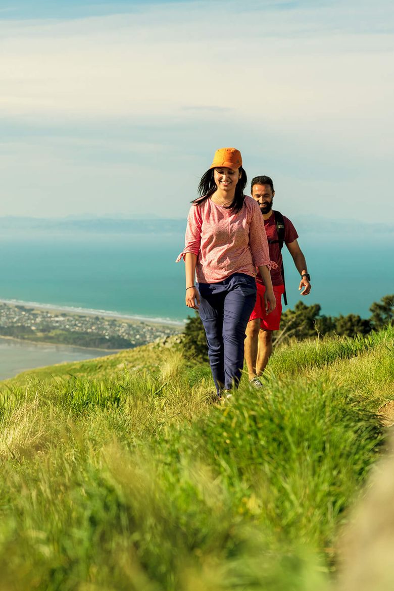 Friends walking in the Port Hills Christchurch with the Christchurch coastline in the background.