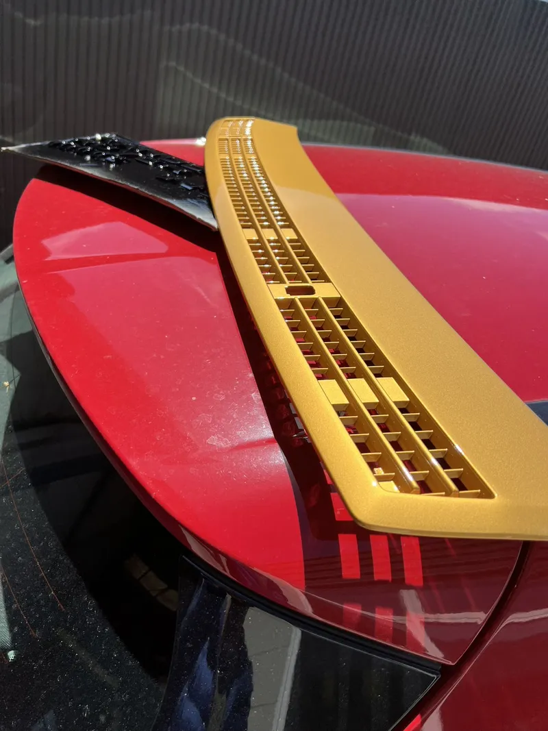 Close up of a gold rear spoiler fitted to a freshly painted red car