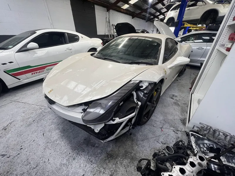 White Ferrari 458 with front-end collision damage in the workshop
