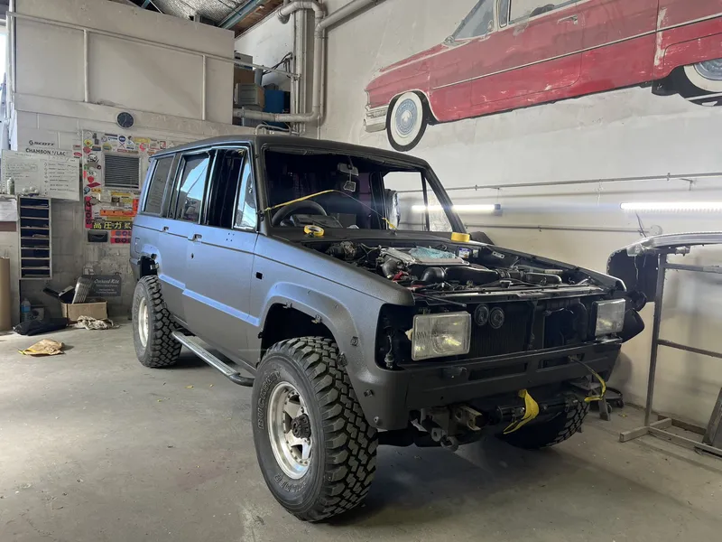 Grey four wheel drive in the workshop with the bonnet up and front panel work under way