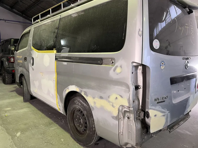 Silver Nissan NV350 van with the rear quarter panel stripped and primed