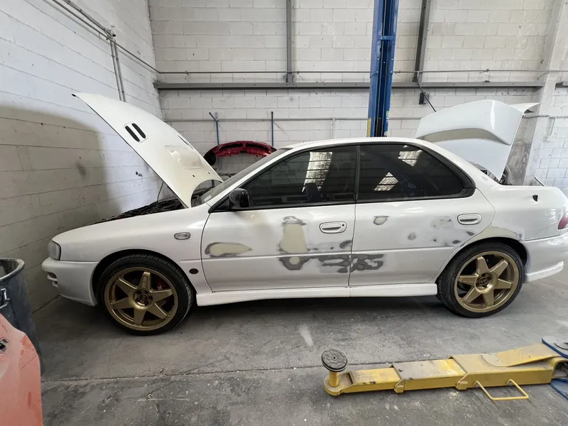 White Subaru Impreza in the workshop with panel repairs marked out