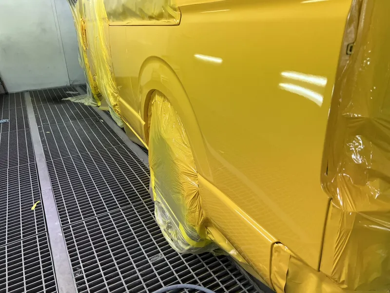 Yellow van freshly resprayed in the spray booth with the masking still in place