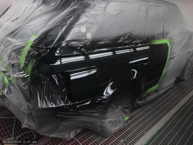 Black car wrapped in plastic and masked with tape ready for spray painting