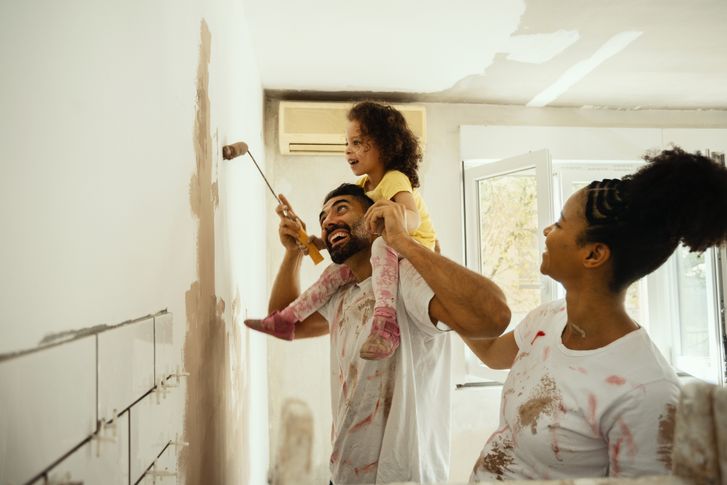 Family painting a wall together while renovating their home