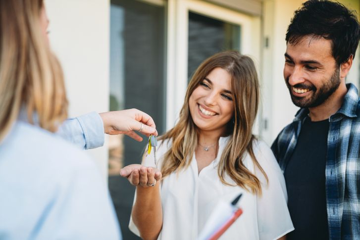 Real estate agent handing house keys to a smiling couple