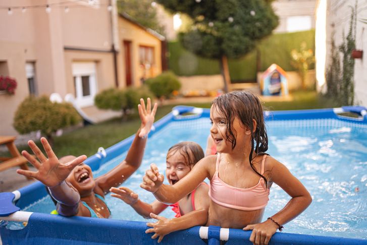 Children playing with a ball in a backyard pool