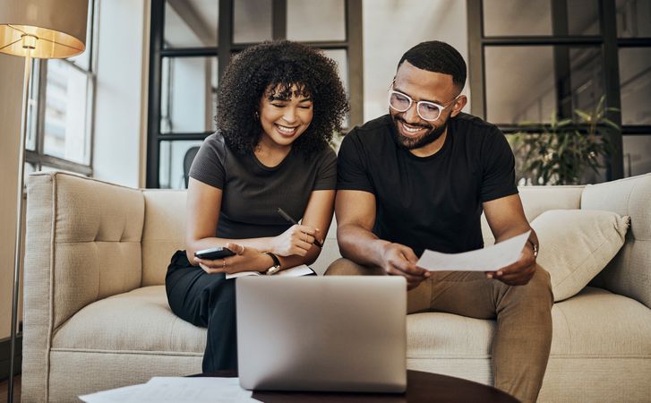 Couple reviewing paperwork on a laptop as they compare loan options