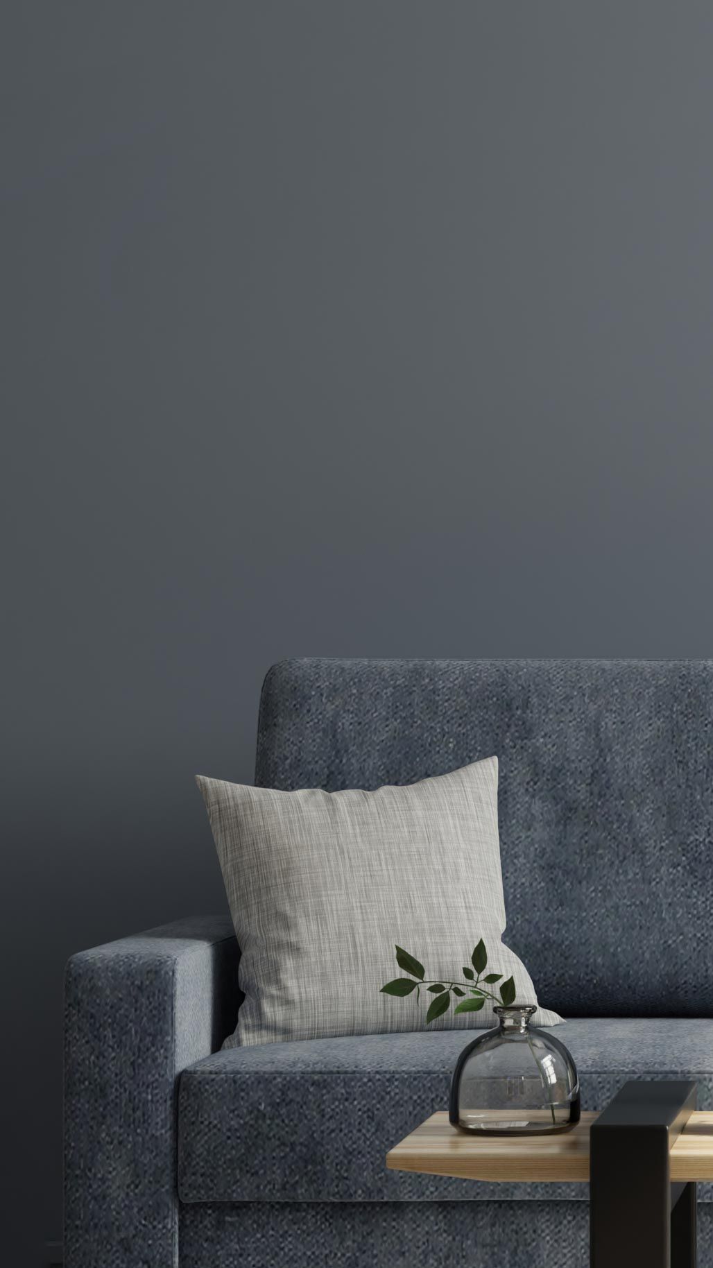 A modern living room with a blue sofa, gray and white cushions, and a wooden table holding decorative vases and books against a dark wall.