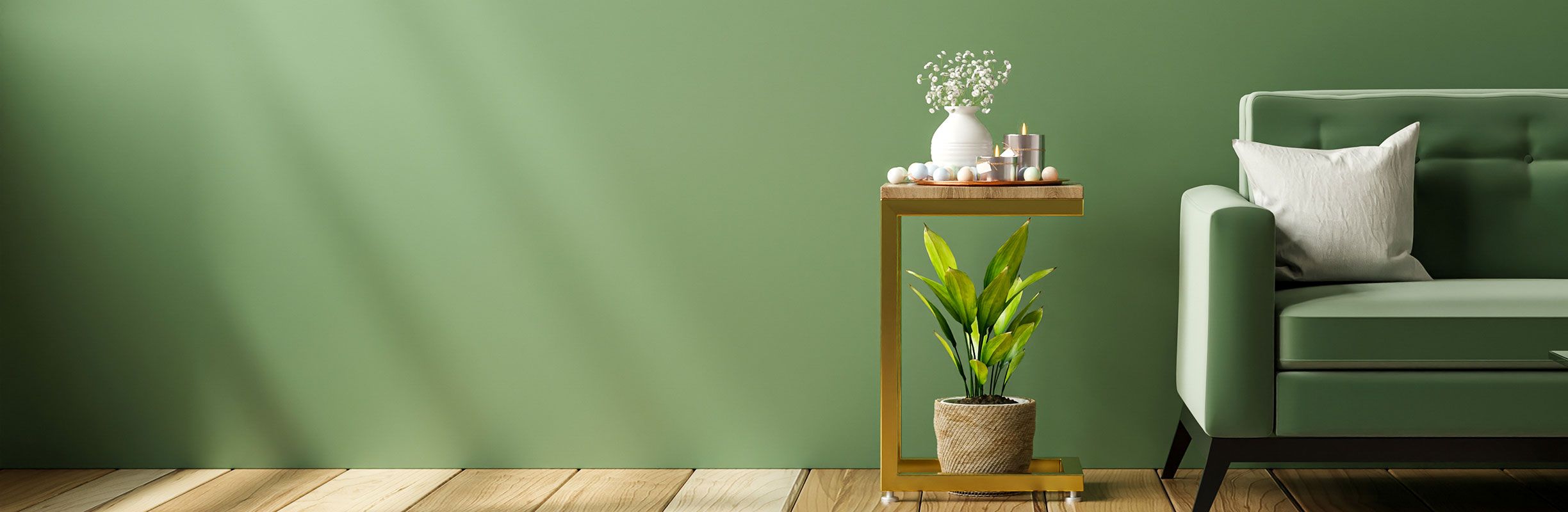 A cozy living room with a green sofa, a white pillow, a side table with decor items, and a potted plant against a matching green wall.